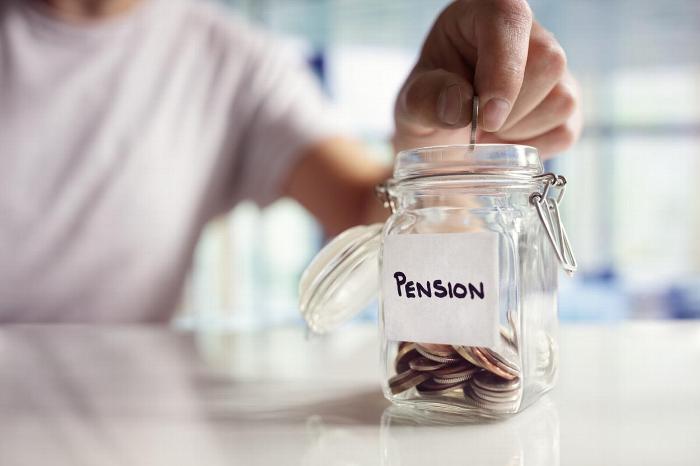 Someone adding pennies to a jar labelled 